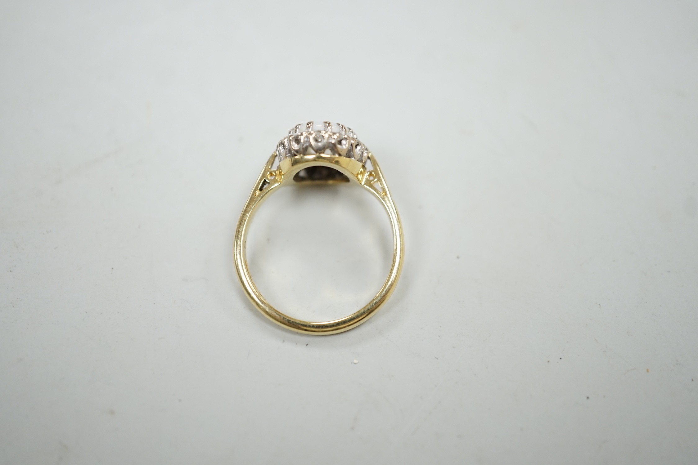 A modern 18ct white gold white opal and diamond set oval cluster ring, size M, gross weight 4.3 grams.